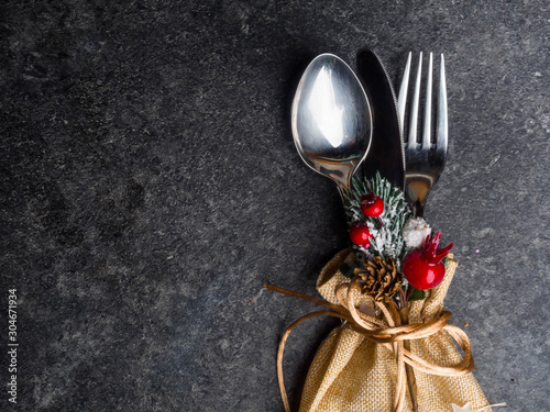Festive Christmas table place setting with cutlery, pine branche, red berries, rose hip, cone. Winter holidays and festive background. Christmas eve dinner, New Year food lunch. View from above, top