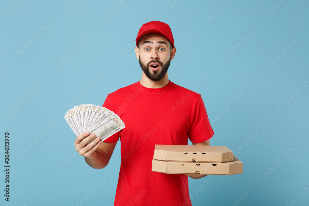 Delivery man in red workwear giving food order pizza boxes isolated on blue background, studio portrait. Professional male employee in cap t-shirt print courier. Service concept. Mock up copy space. Delivery man in red workwear giving food order pizza boxes isolated on blue background, studio portrait. Professional male employee in cap t-shirt print courier. Service concept. Mock up copy space.