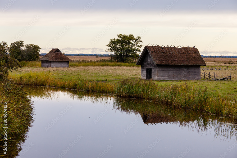 Traditional wooden buildings with thatched roofs in Estonia, Matsalu National Park. Huts by the river.