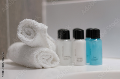 Mini bottles with cosmetic products and towels on table, space for text. Hotel amenities