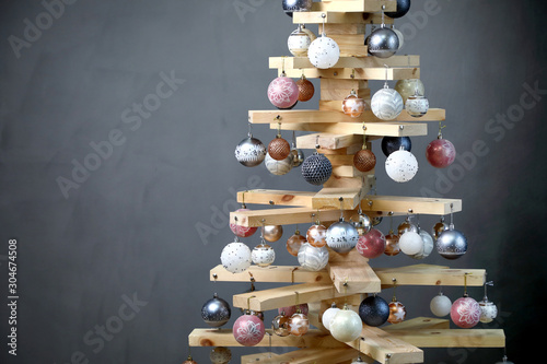 Alternative Christmas tree .  Christmas tree in the new year of wood boards, decorated with balls, on a gray background . horizontally, copy space .