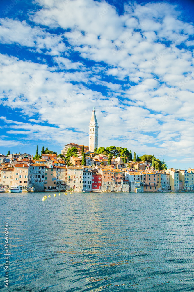 Beautiful town of Rovinj on seaside in Istria, Croatia. Old historic houses and cathedral tower bell on the peninsula on Adriatic sea coastline.