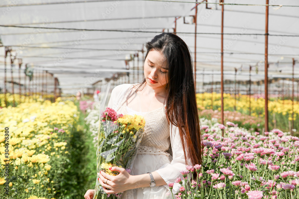 Portrait young beautiful asian woman in white dress relaxing at chrysanthemum flower garden