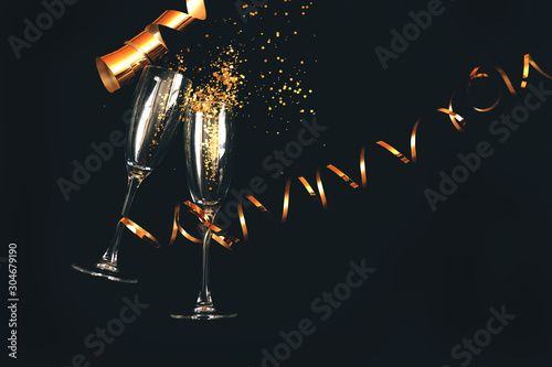 Canvas Print Two champagne glasses with golden sparkles over black background