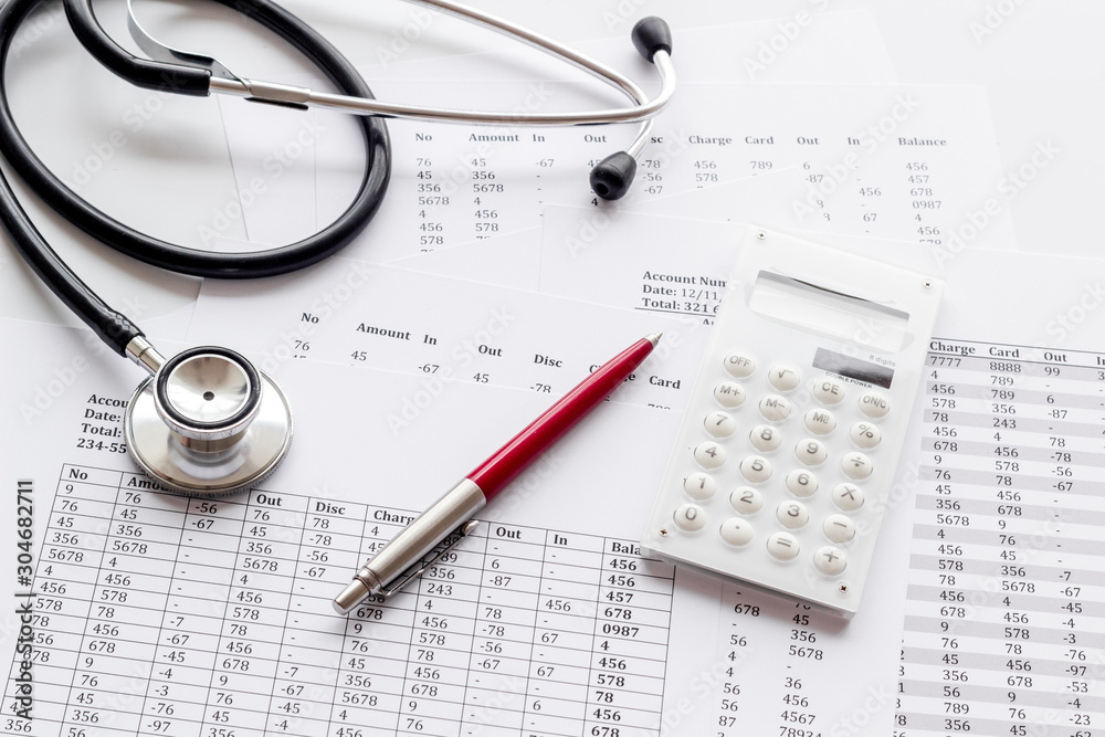 Health insurance concept. Stethoscope near financial documents and calculator on white background Health insurance concept. Stethoscope near financial documents and calculator on white background