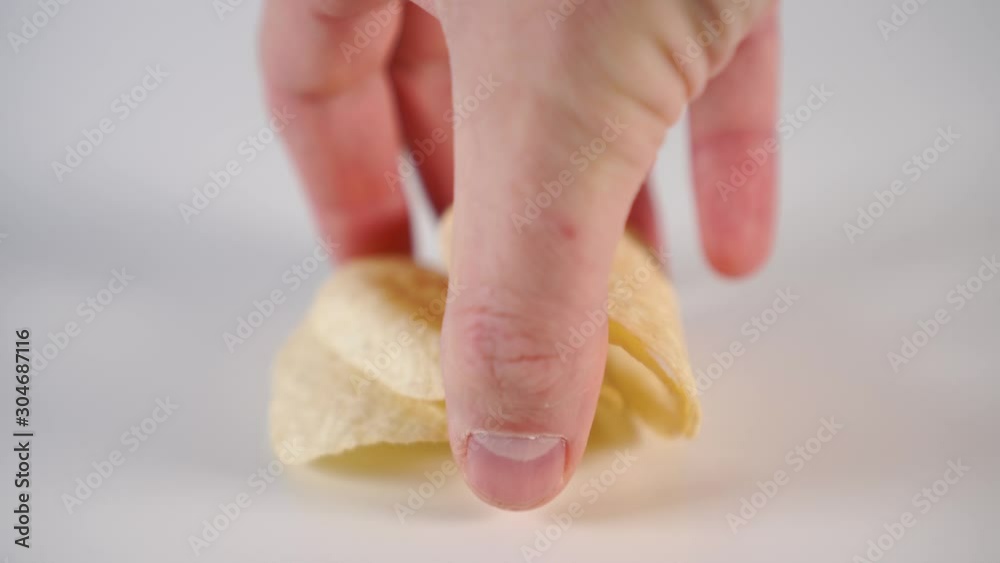 A man's hand removes a red Apple from the white table and puts down potato chips. The concept of eating fast food food instead of natural vitamin foods A man's hand removes a red Apple from the white table and puts down potato chips. The concept of eating fast food food instead of natural vitamin foods