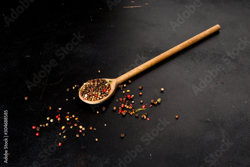 Wooden, long spoon with sprinkled pepper. Close-up shot