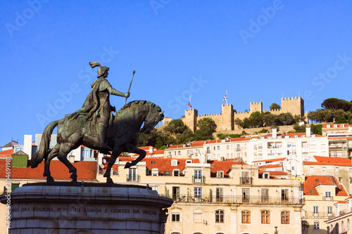 Lisbon, Portugal - May, 22nd, 2018 : Equestrian statue of King John I in the Praça da Figueira with Sao Jorge Castle walls and towers in background. photo