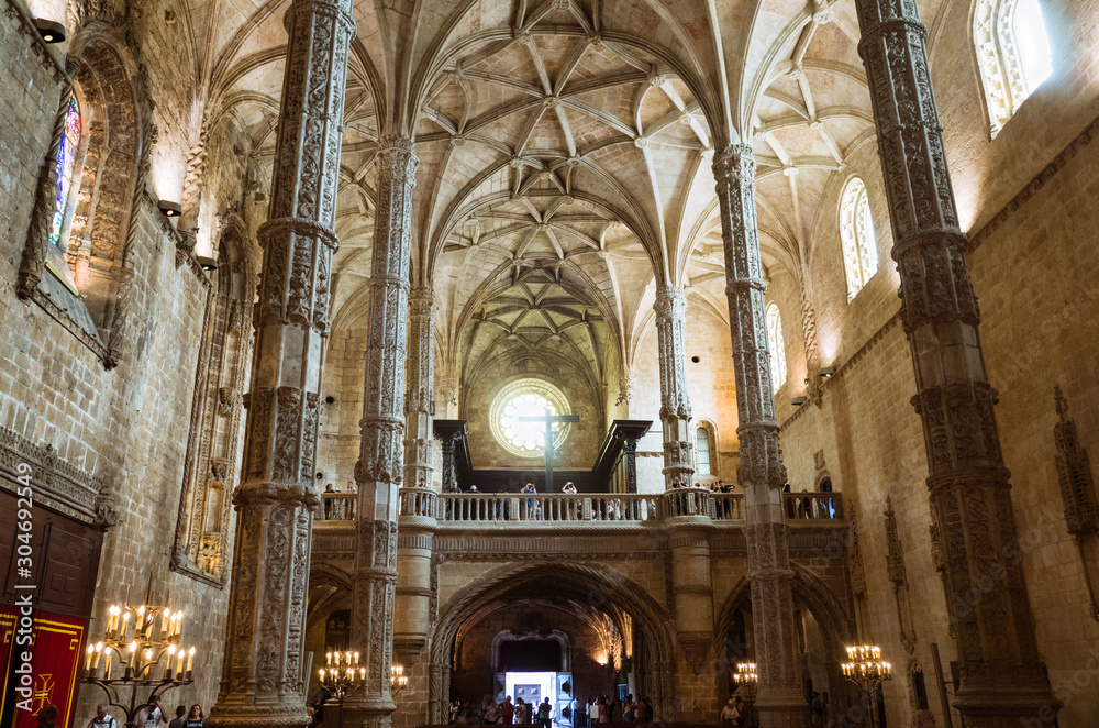 Lisbon, Portugal: Ornate pillars and ceiling of  the Jeronimos Monastery, one of the most prominent examples of the Portuguese Late Gothic Manueline style. Incidental people in background.