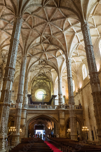 Lisbon, Portugal Ornate pillars and ceiling of the Jeronimos Monastery, one of the most prominent examples of the Portuguese Late Gothic Manueline style. Incidental people in background.