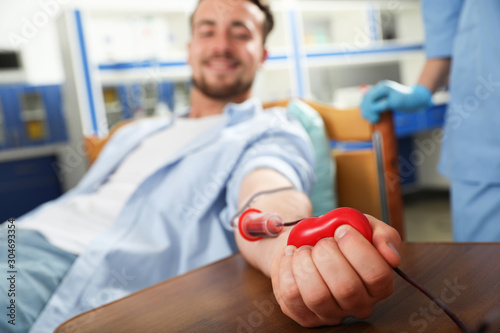 Young man making blood donation in hospital, focus on hand