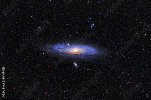 Andromeda Galaxy (M31) and its satellite galaxies (M32 and M110) in Andromeda constellation against widefield starry sky