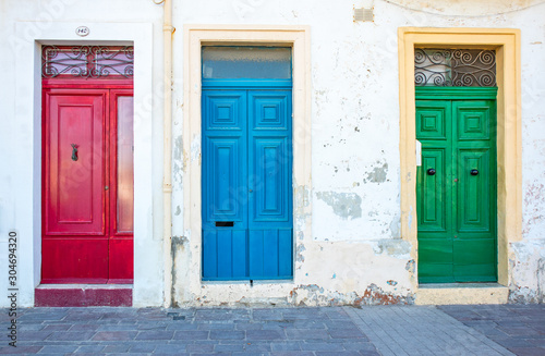 Three typical traditional maltese doors in Marsaxlokk village. Red, blue, green doors. Morning. Malta country © Karina Movsesyan
