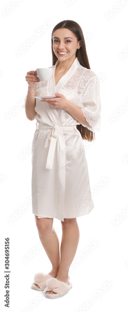Young woman in silk robe with cup of beverage on white background Young woman in silk robe with cup of beverage on white background