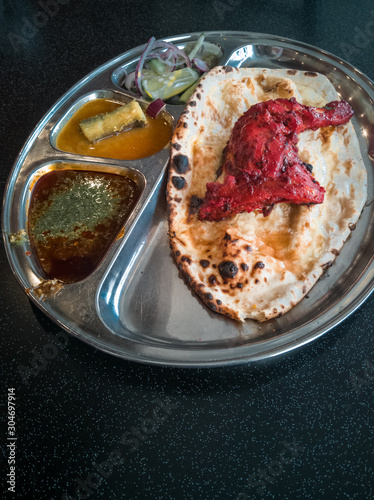 Indian Cuisine Tandoori Roti And Chicken Served in Metal Plate Also Called Chapati, Flatbread, Naan or Nan Bread on Dark Background