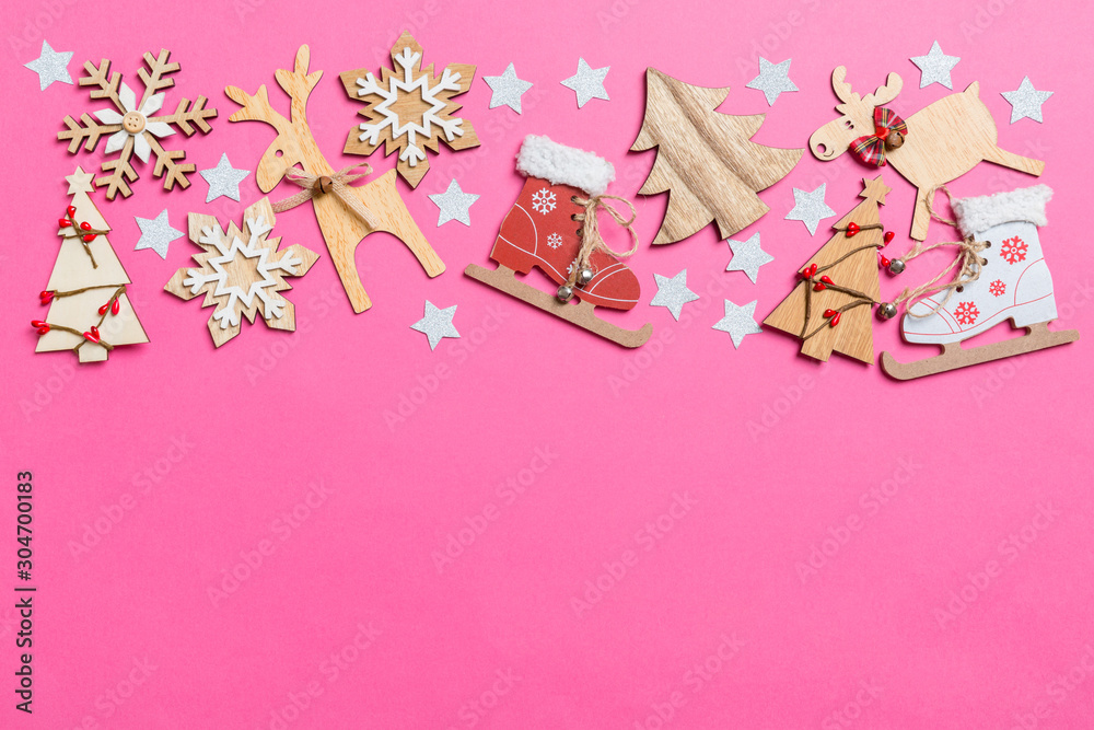 Top view of pink background decorated with festive toys and Christmas symbols reindeers and New Year trees. Holiday concept with copy space