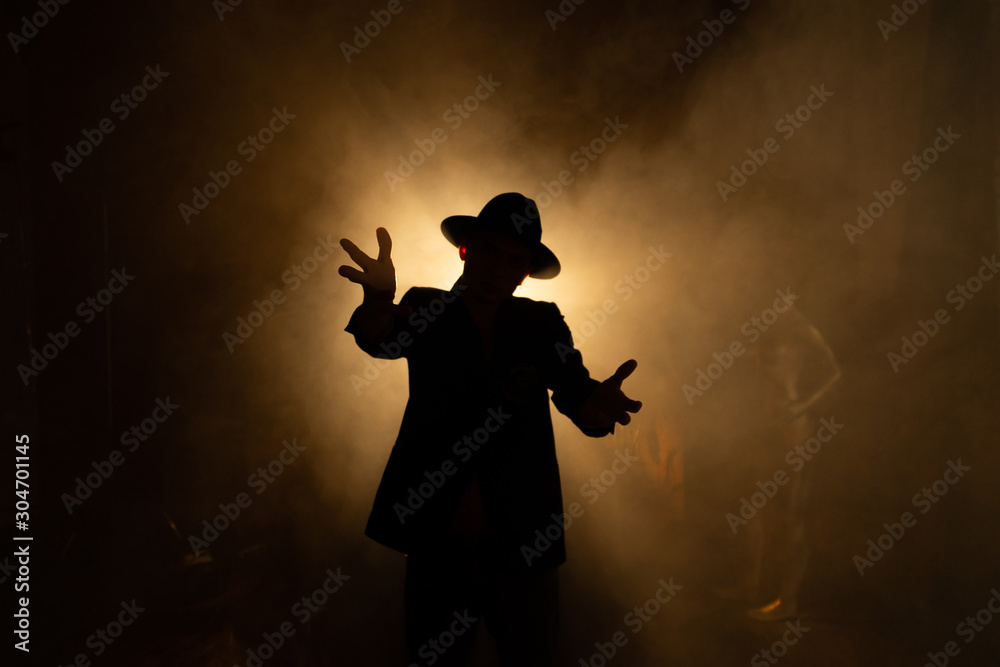 Silhouette of a man in a hat against the light, backlit guitar concert, performance with contrast