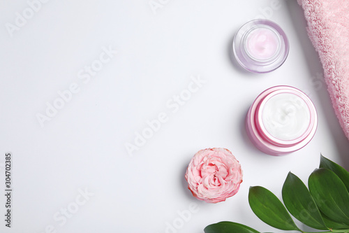Flat lay composition with jars of cream on white background. Space for text