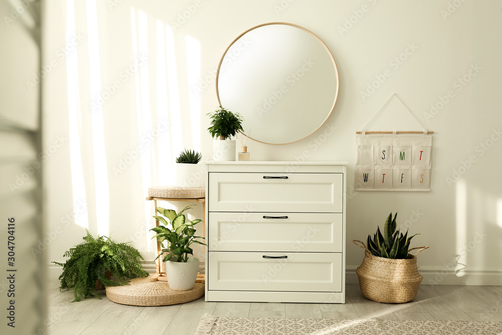 Stylish room interior with chest of drawers and round mirror Stock