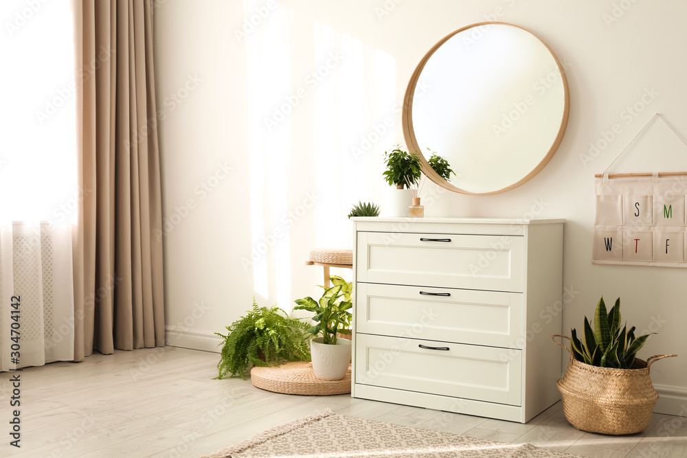 Stylish room interior with chest of drawers and round mirror Stock Photo