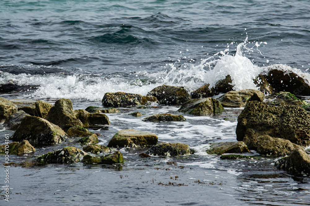 Breathtaking sea of traditional emerald color. Foamed sea waves break on stones near shore. Blue, green and emerald colors are perfect backdrop forrelaxing theme. Elegant nature concept for design. Breathtaking sea of traditional emerald color. Foamed sea waves break on stones near shore. Blue, green and emerald colors are perfect backdrop forrelaxing theme. Elegant nature concept for design.