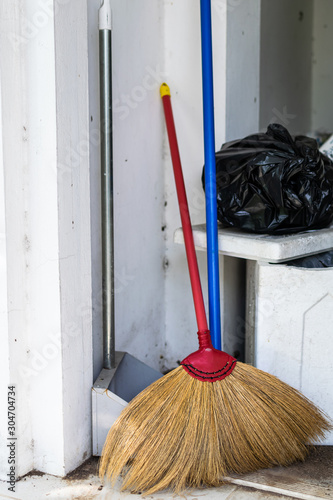 A broom and a dustpan are stored in the backyard storage room