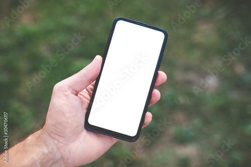 Male hand holding black cellphone with white screen outdoor, close up