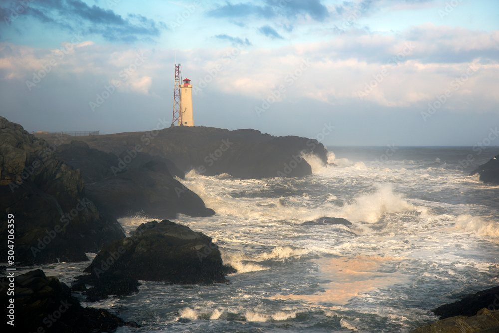 Fototapeta premium light house on the cliff with the wild sea wave in Iceland