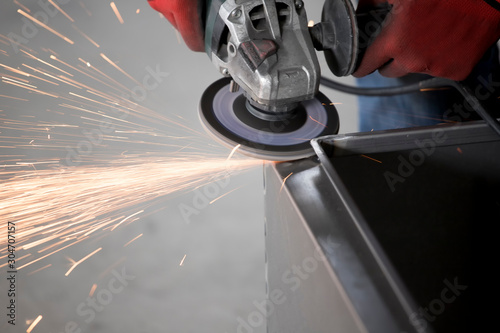 Worker cutting metal part using hand Angle Grinder Machine. Freeze motion spark