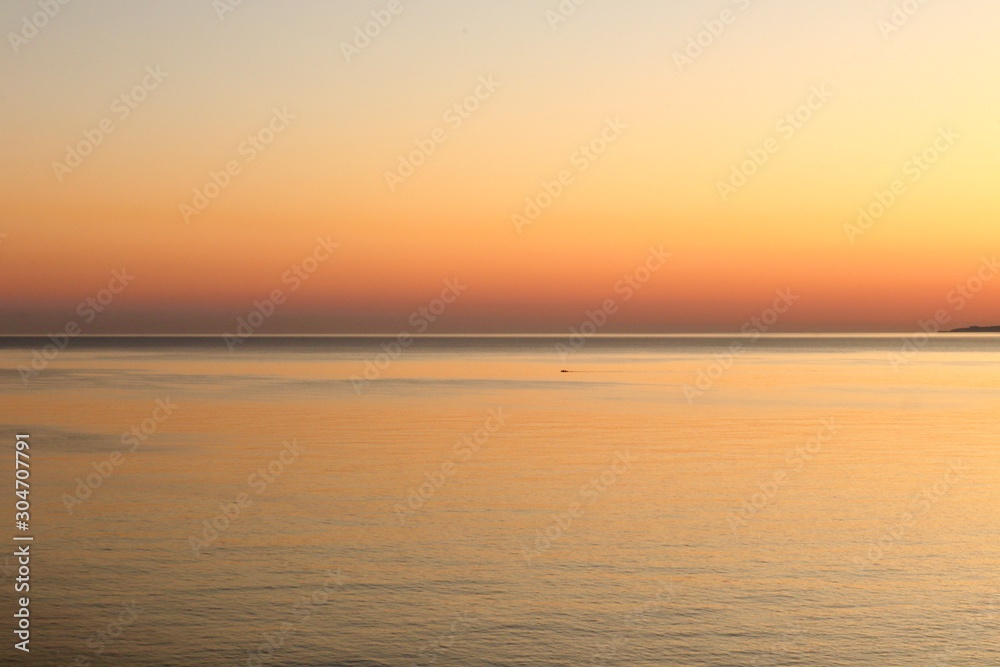 Orange and red sunset colors in the sky and in the calm smooth water