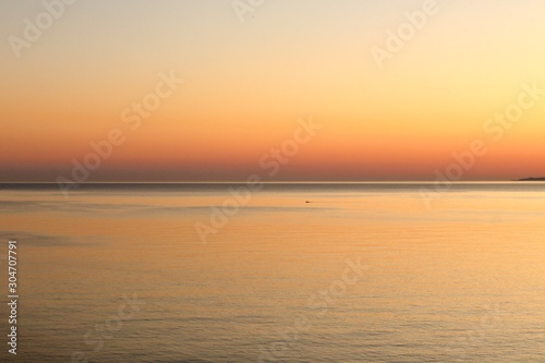 Orange and red sunset colors in the sky and in the calm smooth water © Angela Harrod