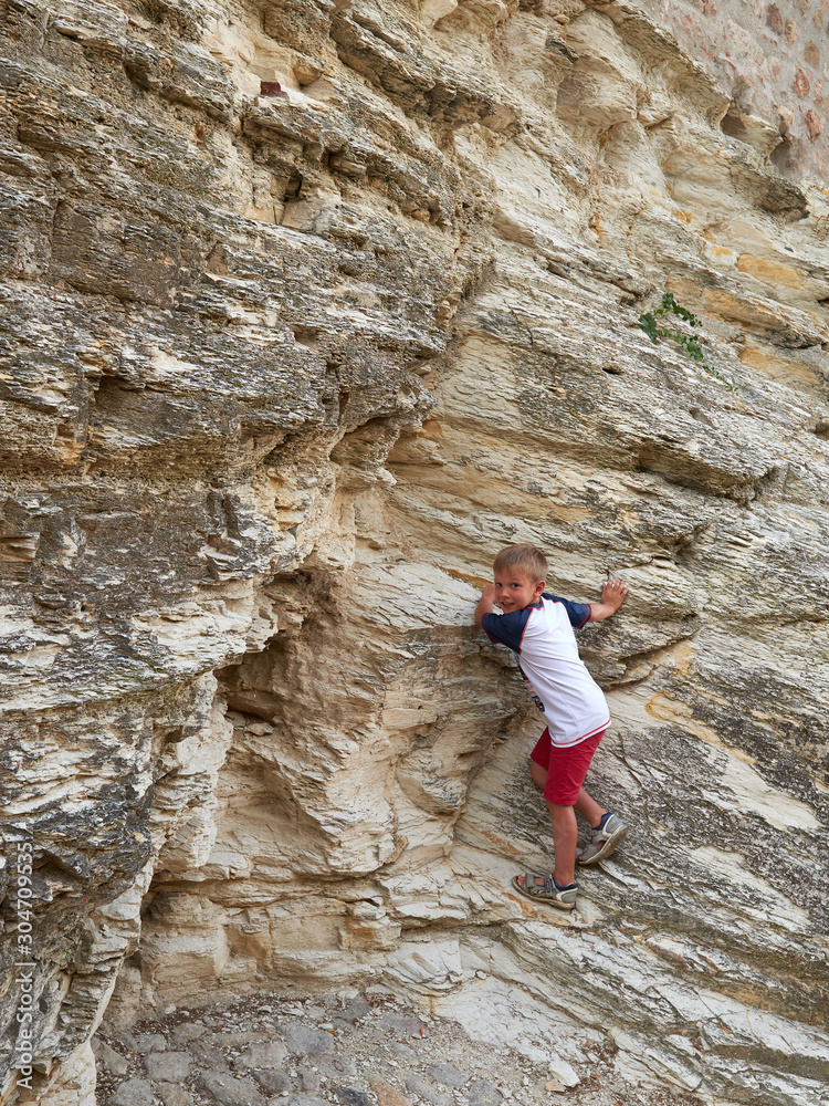 boy climbs a rock on the street of the old town ARKUA PETRARKA, ITALY