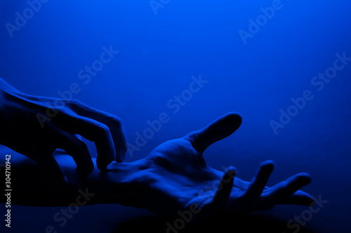 Hands in monochrome blue contrast neon light. Man showing hand palm gesture sign. Artistic photography.