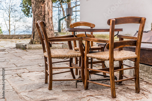 A wooden table and 3 chairs vintage style   in a stone square at the village of Kissos on Pelion Greece 