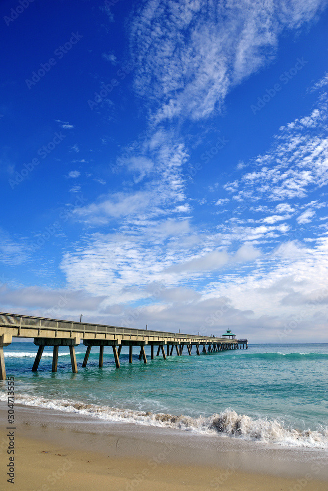 Seashore landscape with fishing pier with beach and waves in Atlantic Ocean in Florida