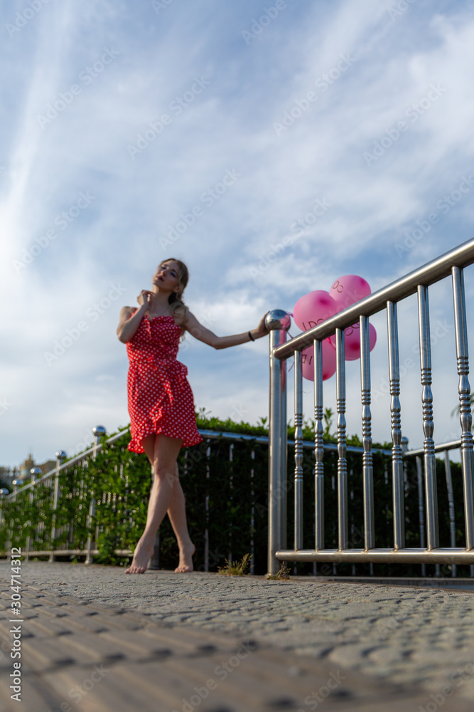 girl in a red polka-dot dress with pink balloons in the city
