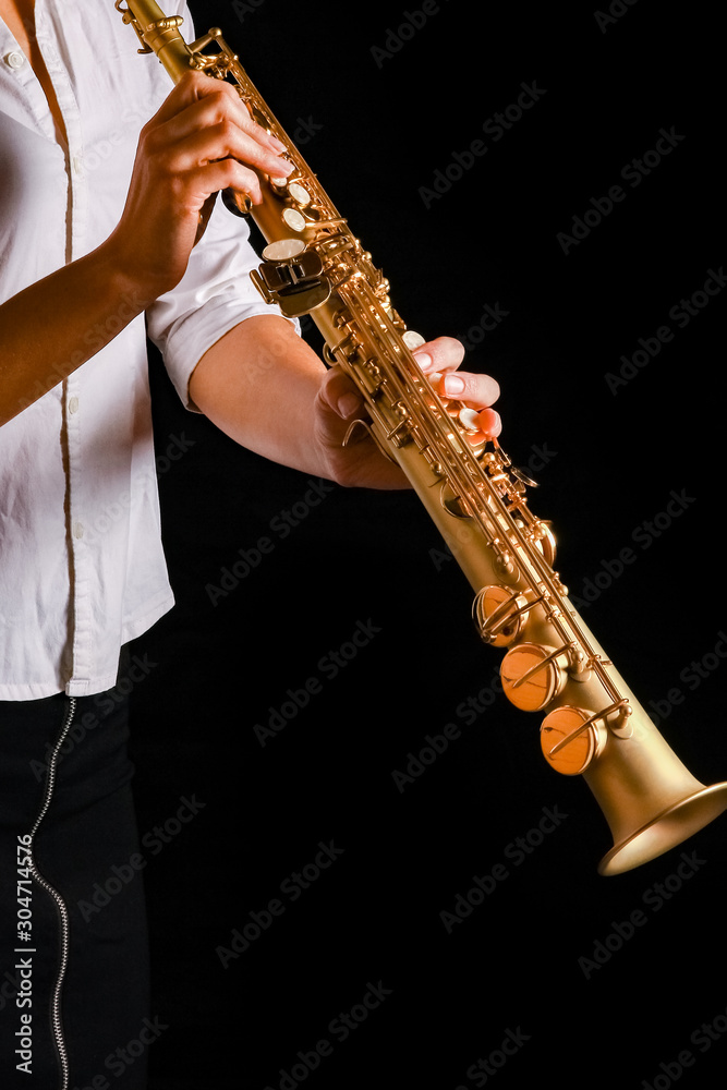 Obraz premium soprano saxophone in the hands of a girl on a black background