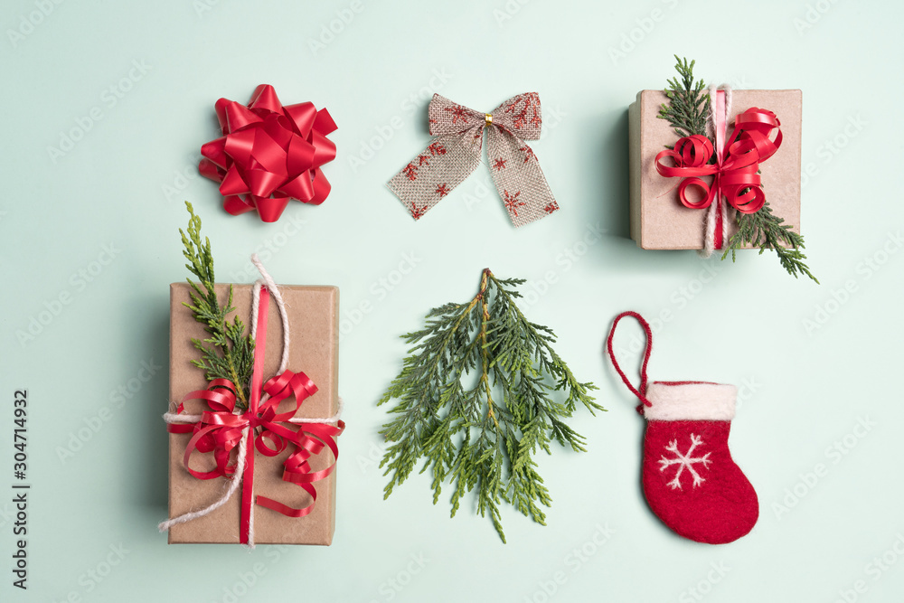 Christmas inspired flat-lay taken from above of presents, gifts, ribbon, bow, stocking and Christmas tree branch. Background colour green with Green, Red, natural colours. Christmas inspired flat-lay taken from above of presents, gifts, ribbon, bow, stocking and Christmas tree branch. Background colour green with Green, Red, natural colours.