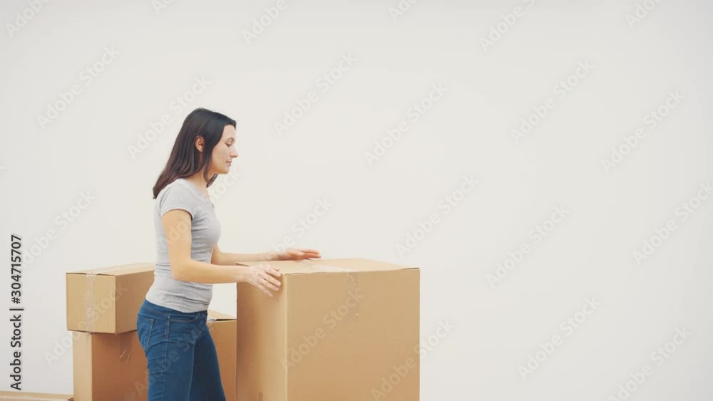 Pretty young woman is thinking how and where to remove heavy carton boxes. Pretty young woman is thinking how and where to remove heavy carton boxes.