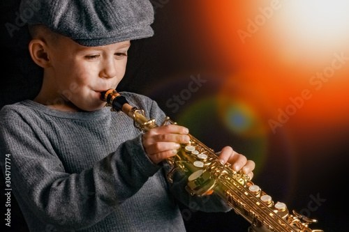 happy child plays saxophone in studio photo