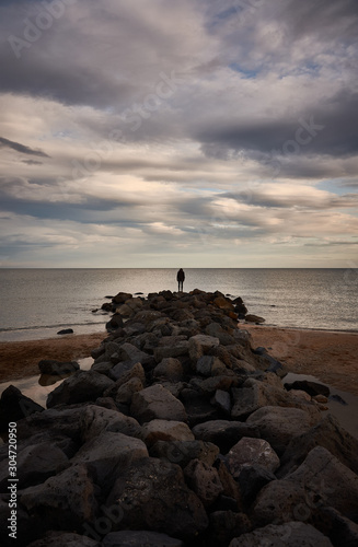 A man contemplates the Mediterranean Sea from the rocks of the Plage Baleine in Sète. France