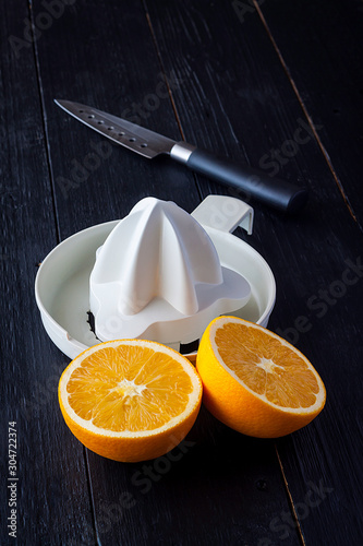 ORANGE CUT TOGETHER WITH EXPRESSOR AND KITCHEN KNIFE ON WOODEN TABLE photo