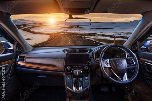Looking through a car windshield with sunset and road in winter. Travel in car.