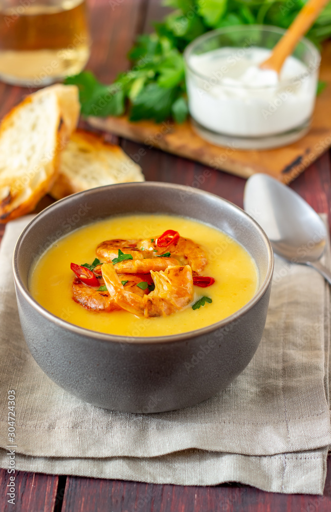 Cheese cream soup with grilled shrimp on a wooden background. Cheese cream soup with grilled shrimp on a wooden background.
