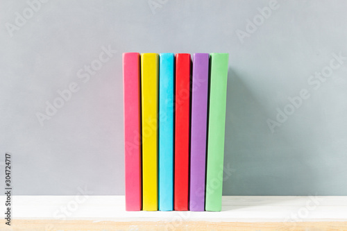 multicolour books on a wooden shelf and gray wall. with copy space