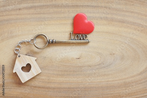 House keyring and love shape key on vintage wooden table. Decorated with mini heart as sweet gift for lover or family member. Home sweet home concept.