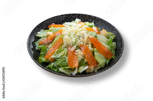 Fresh green salad with salmon fish in beautiful black modern plate