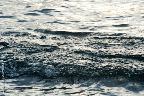 Small waves break before reaching the beach at sunset