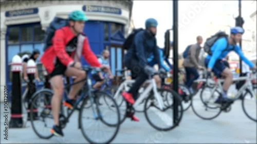 Lots of cyclists cycling arcross a busy road in traffic on the roads waiting at the lights photo