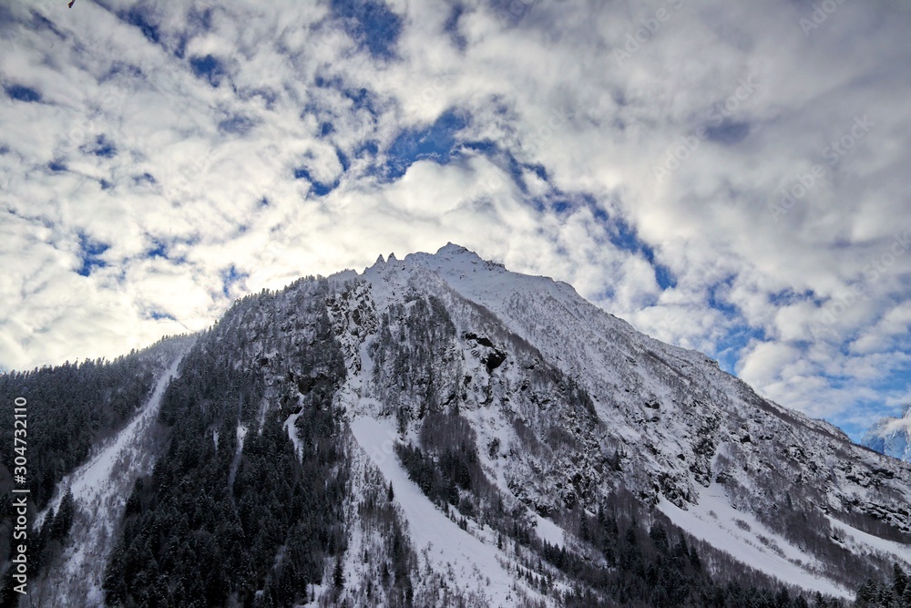 Obraz premium Snowy Mountains peaks in the clouds blue sky Caucasus